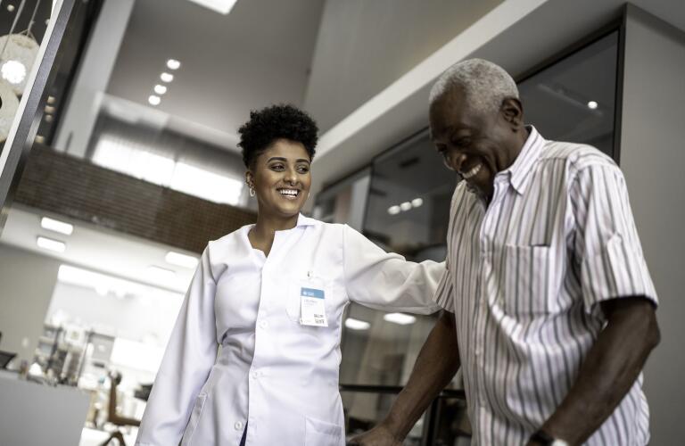 caretaker assisting senior man with walker in medical facility