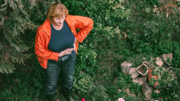 a woman is gardening and noticing lower abdominal pain