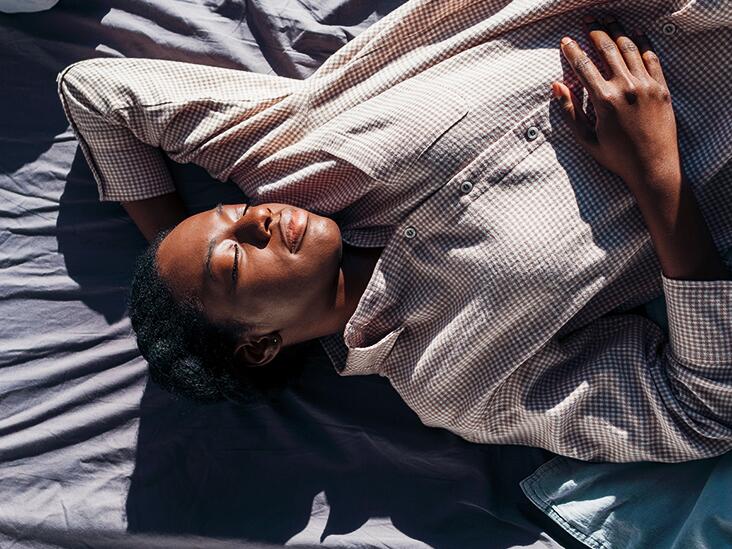 Woman resting on a bed with hand on upper abdomen