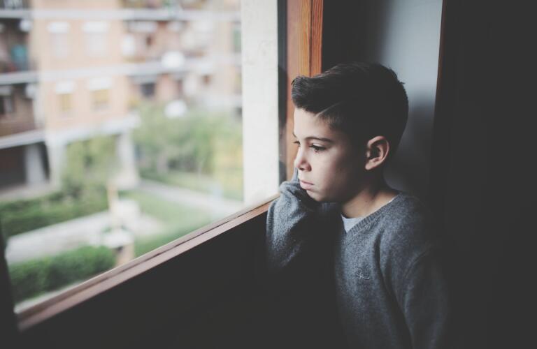 Young Hispanic boy staring out window lost in thought
