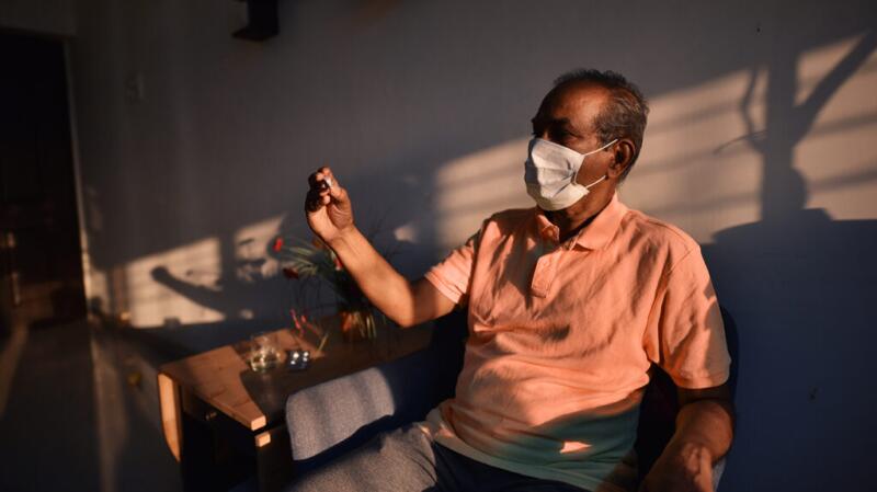 man with face mask checking thermometer