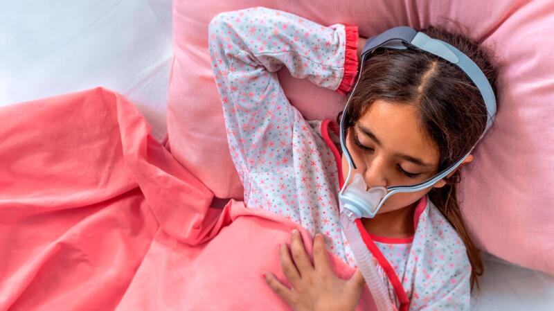 A child is sleeping with a sleep apnea mask.