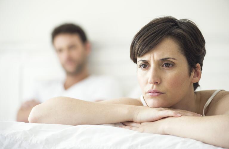 Caucasian couple in bed with woman looking concerned over lack of libido, emotional issues or painful sex