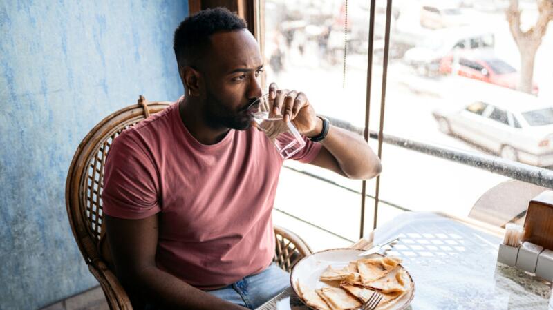 Man eating and drinking water with his meal