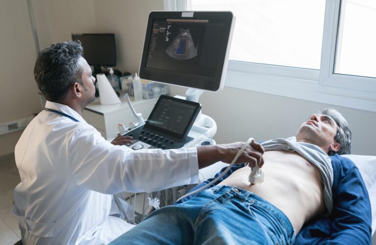 Male doctor performing abdominal ultrasound on male patient