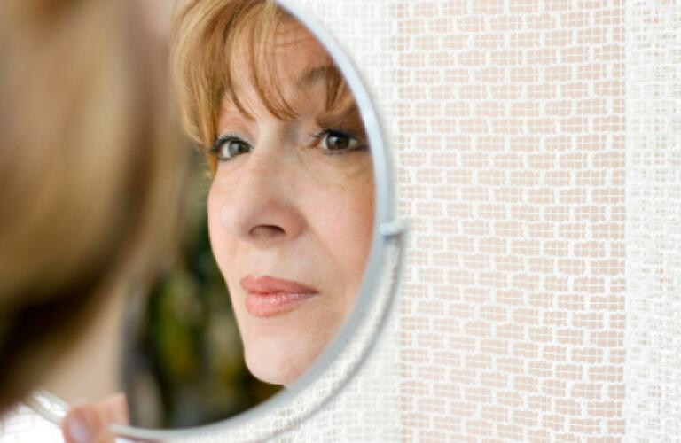 Mature woman looking in mirror