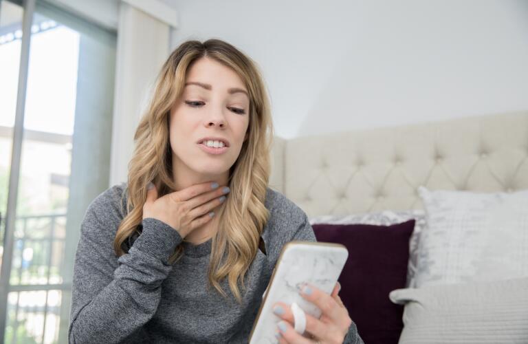 young adult female at home explaining illness to doctor online via video chat