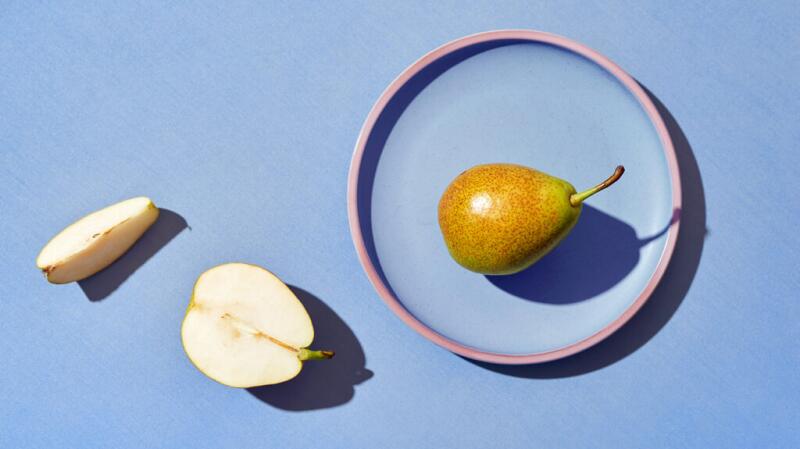 sliced and whole pears on blue background