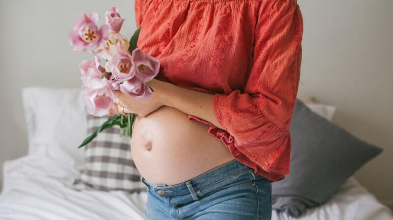 Close up of a pregnant stomach with pink flowers