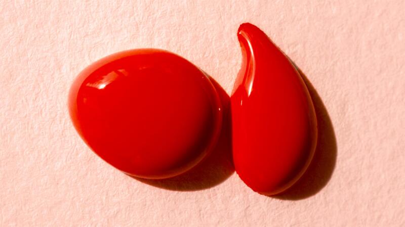 Two splotches of red paint on a pink background