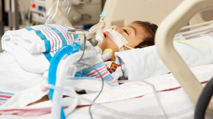 young boy on a ventilator in a coma