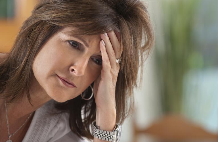 Middle aged woman looking concerned and holding forehead