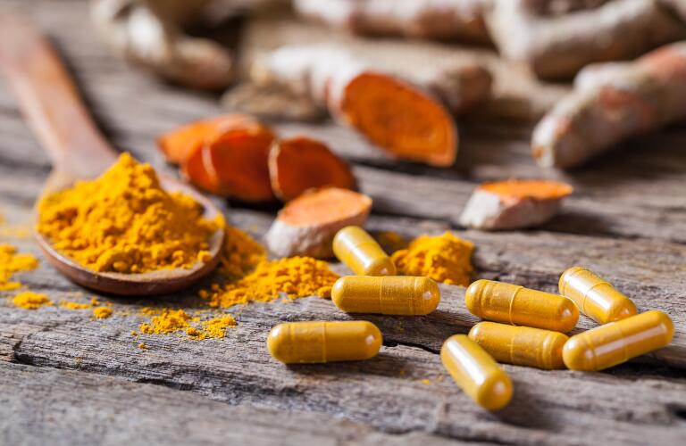 turmeric powder, turmeric capsule and turmeric root on wooden background