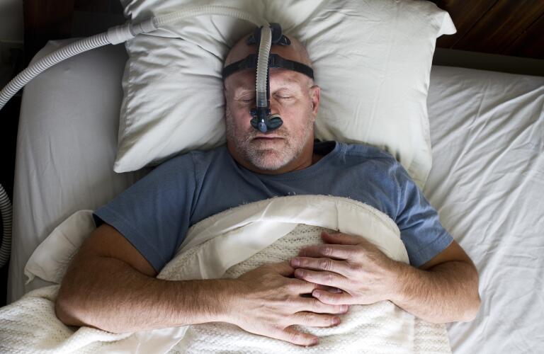man sleeping in bed wearing cpap mask