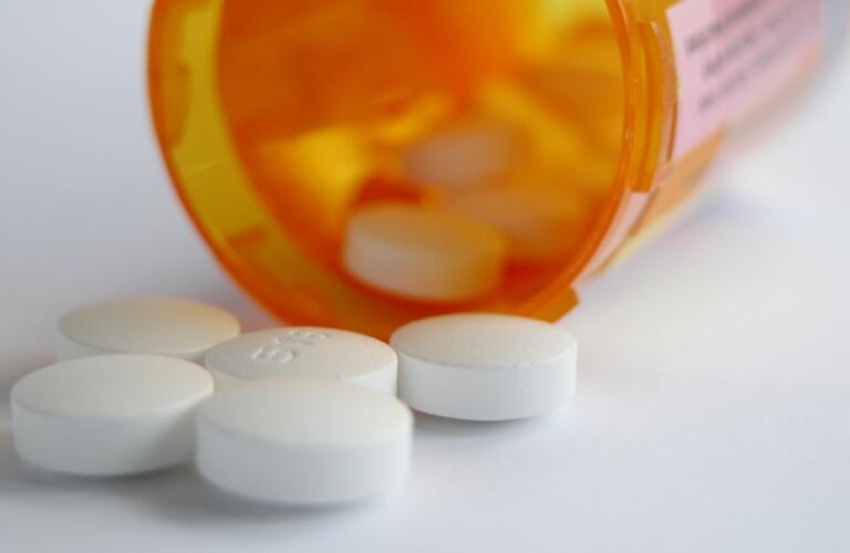 White pills spill from medicine bottle