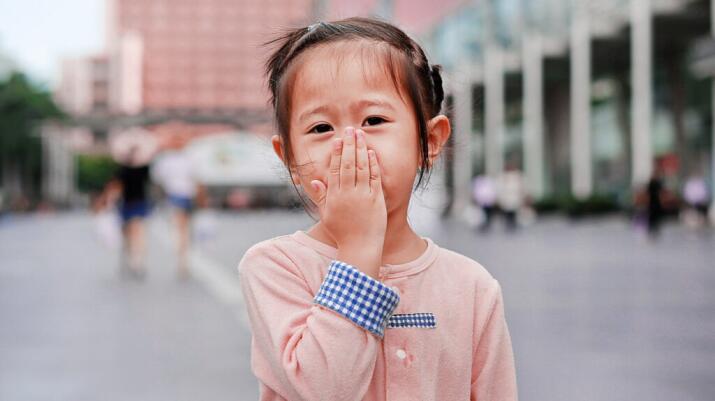 A little girl is covering her nose.