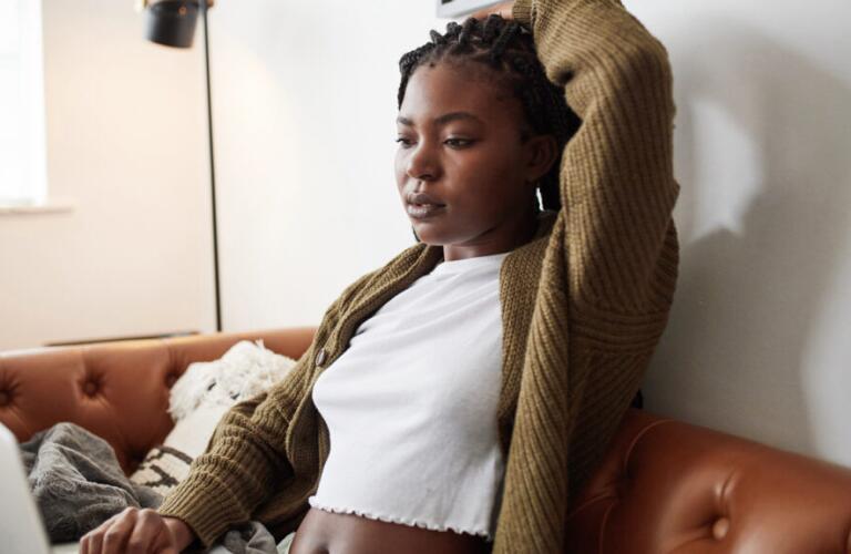Female on couch with left arm up stretching left side