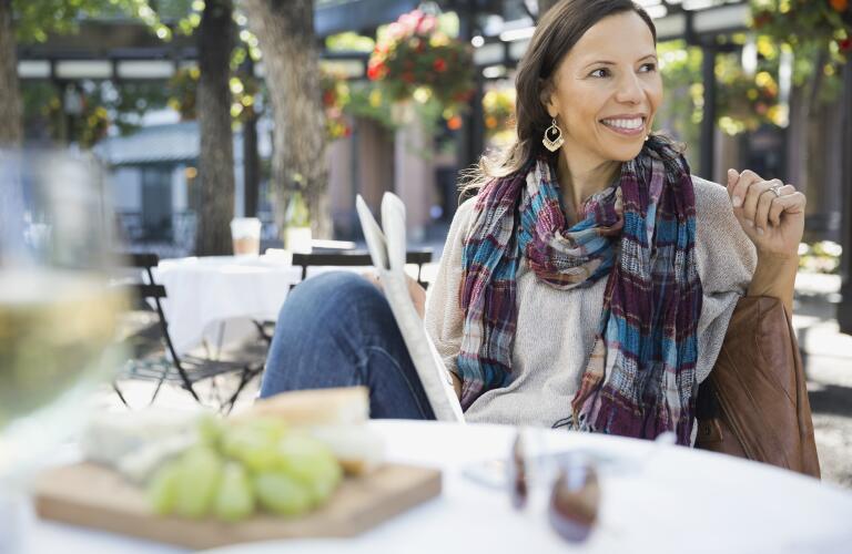 woman sitting at cafe table with newspaper
