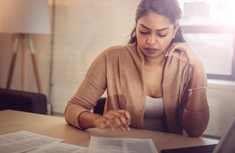 Young Indian American woman looking at paper work on desk