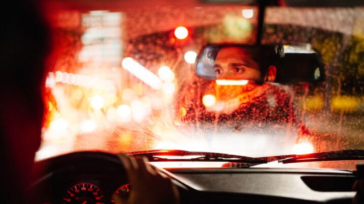 A man is looking in the car mirror.