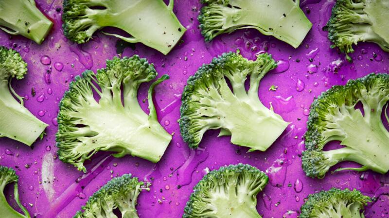 there are slices of broccoli on a purple tray