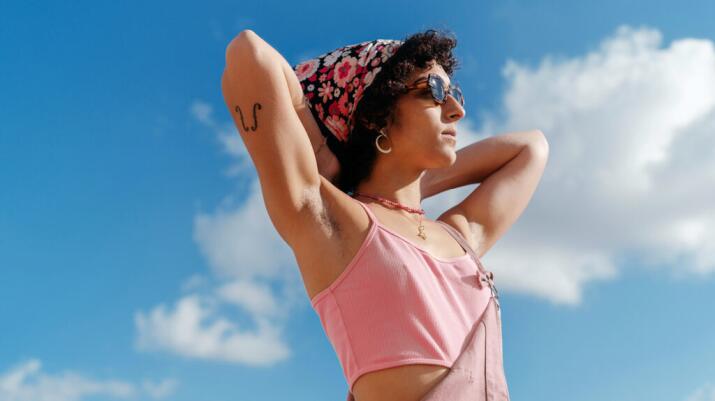 there is a woman with her hands on her neck with a sky background