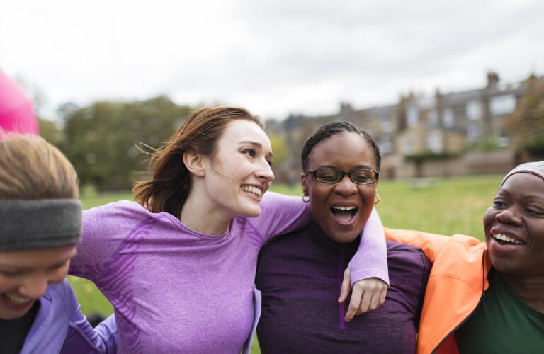 Group of diverse female friends outdoors smiling and laughing after exercising