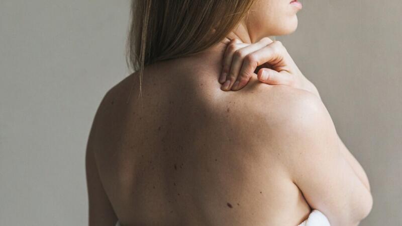 a woman is rubbing her painful back