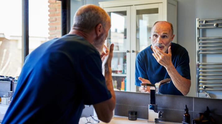 Man checking face and lip in bathroom mirror