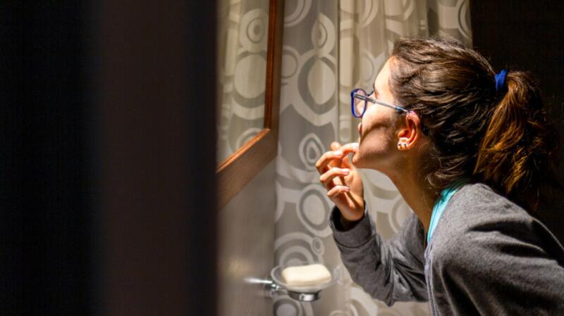 woman looking at mouth in the mirror