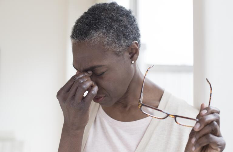 middle aged African American woman taking off glasses and pinching bridge of nose