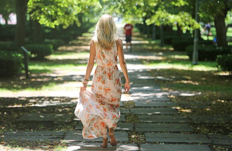 unidentified blonde woman walking away from camera down park path