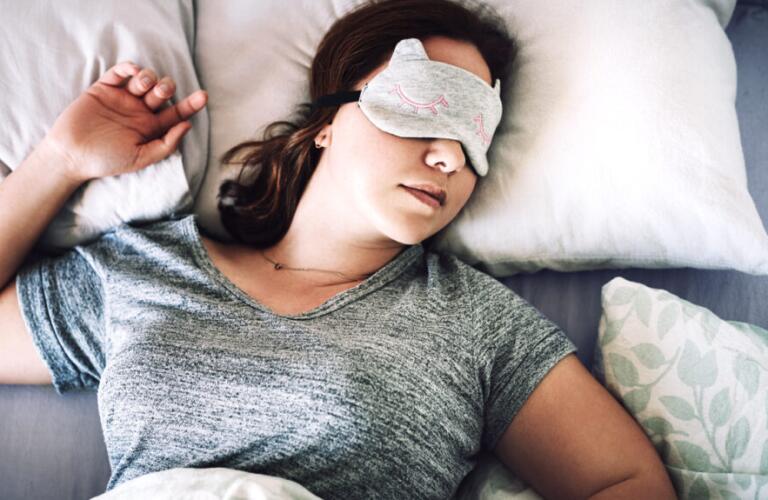 Woman asleep in bed with face mask on lying on back