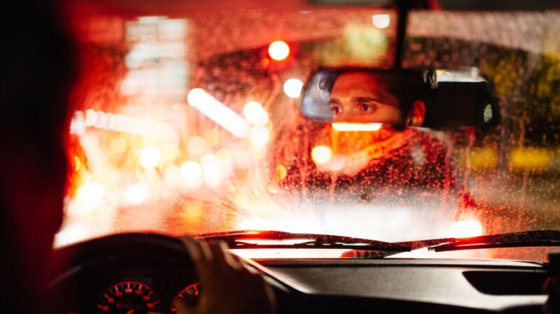 A man is looking in the car mirror.