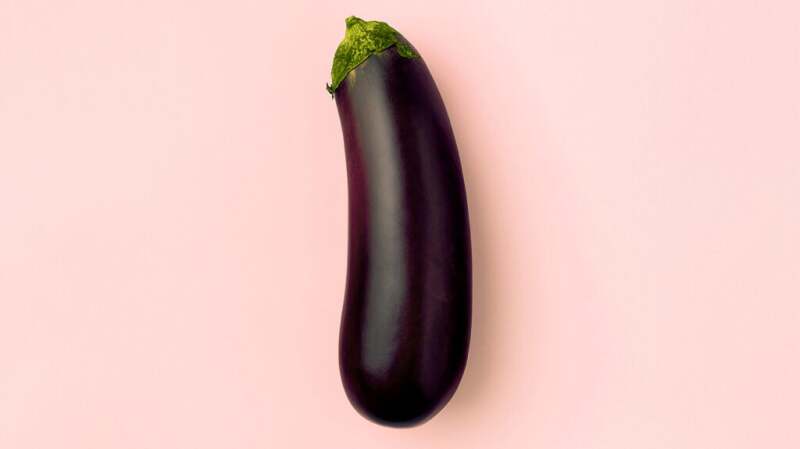 An eggplant set against a pink background