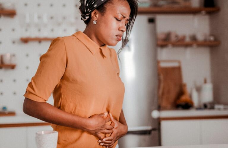 female with stomach pain holding hands against her stomach