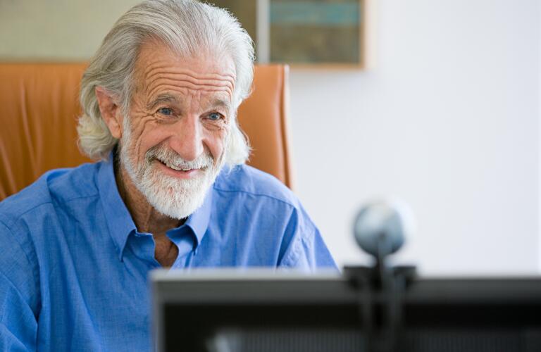 senior man smiling at computer webcam