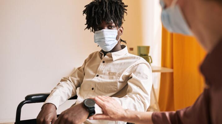 a person is wearing a covid mask and talking to a therapist