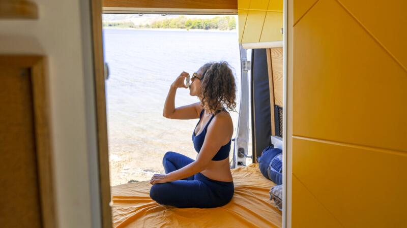 A woman uses an inhaler while sitting outside.