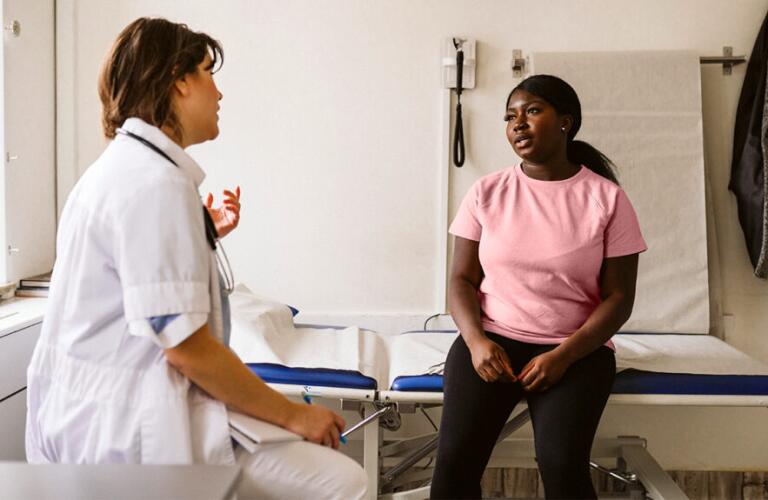 a woman wearing a pink shirt is talking to a doctor