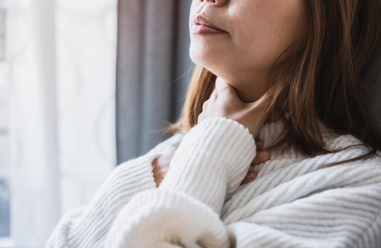 Unseen woman holding throat in pain