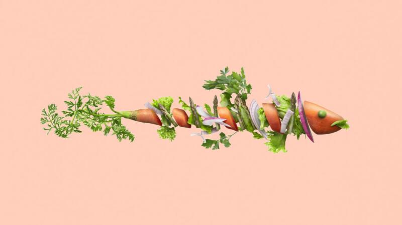 A chopped carrot lies horizontally with layers of fresh herbs and onion between each piece, on a plain beige background.