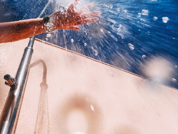 Closeup of a hand checking the temperature of a shower.