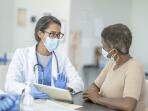 female doctor with digital tablet talking to female patient in medical exam