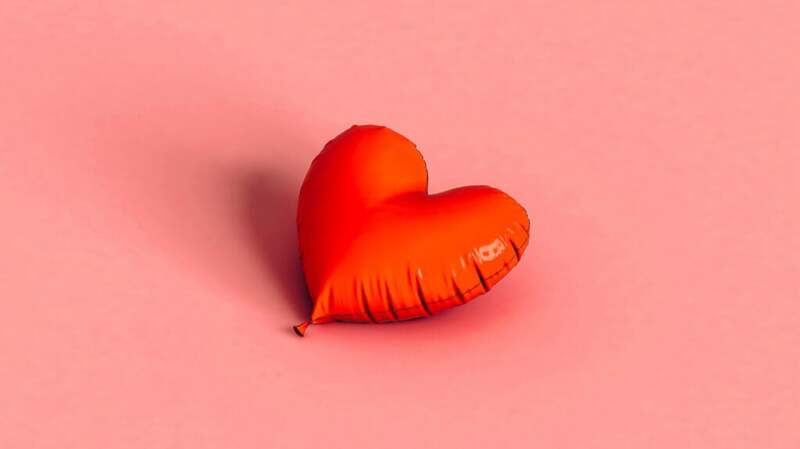 There is a red balloon in the shape of a heart.