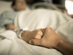 Man holding woman's hand in hospital bed