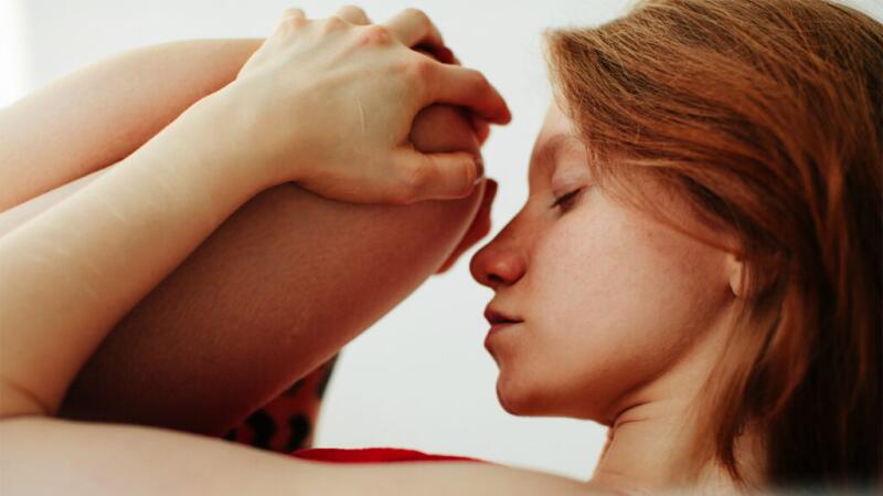 Young woman with pain behind knee stretching and pulling knee up to face
