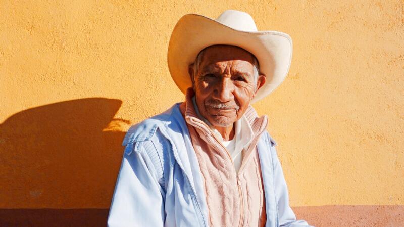 An elderly male wearing a cowboy hat in the sun
