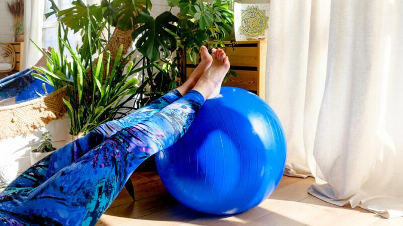 A person is resting their legs on an exercise ball.