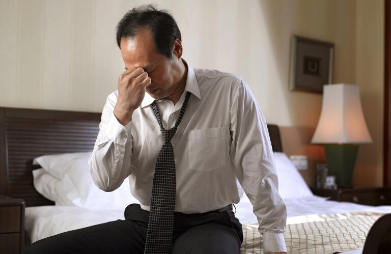 stressed businessman sitting on hotel bed